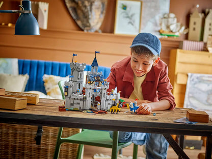 Child playing with a LEGO castle set on a wooden table in a cozy room. (8432448962759)