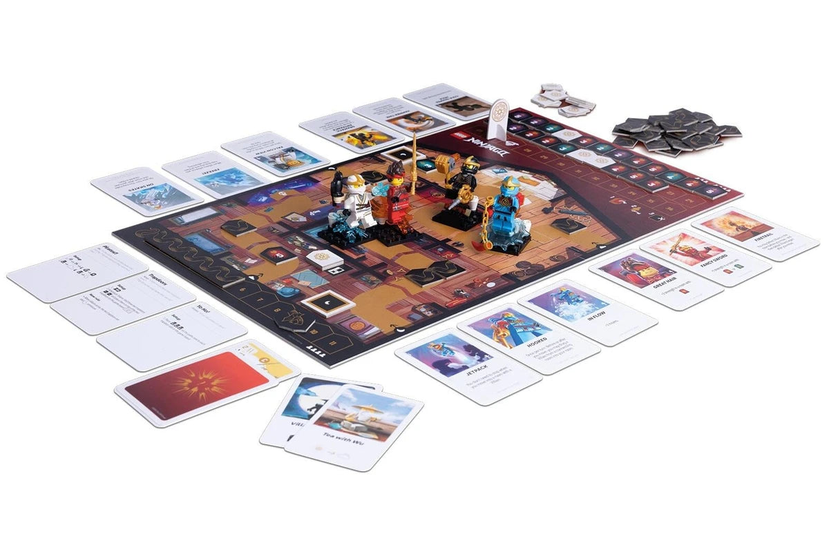 A board game set displayed on a clean white background, featuring a large illustrated game board with LEGO miniatures, numerous player cards, resource cards, and dark  tokens.
