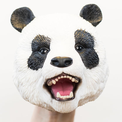 A realistic panda puppet with an open mouth showing teeth and a pink tongue, photographed against a plain light background.