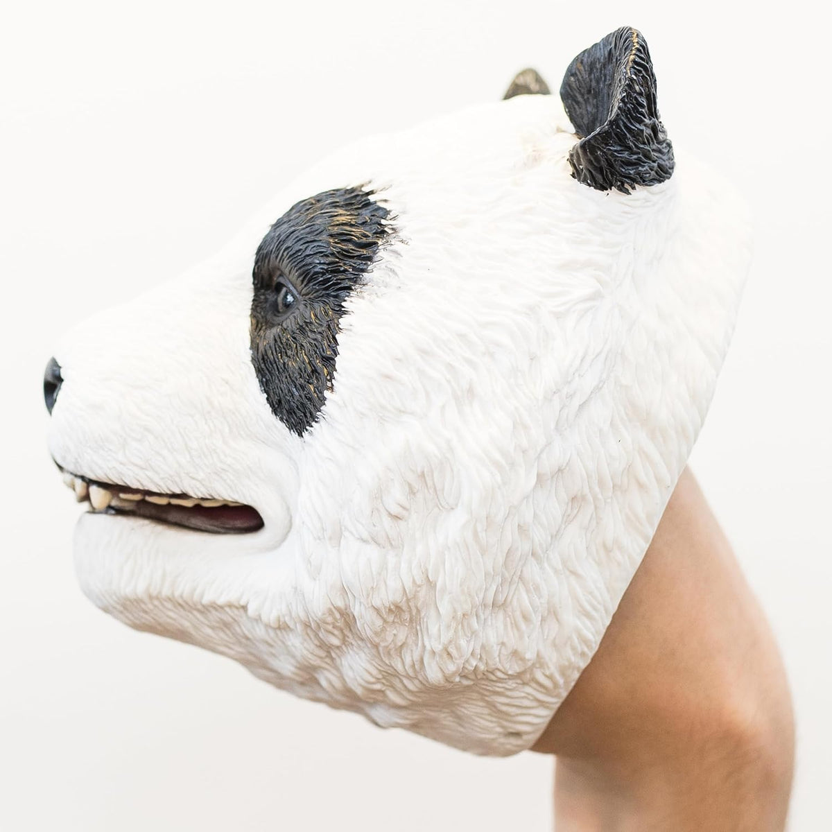 A realistic panda head puppet worn on a person's hand, shown in side profile against a plain white background.