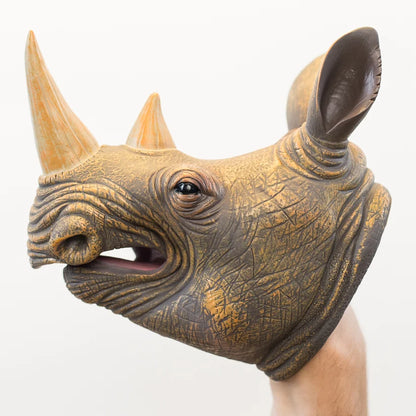 A realistic rhinoceros puppet with textured golden-brown and dark gray skin, featuring two horns and an open mouth, shown on a person's hand against a plain white background.